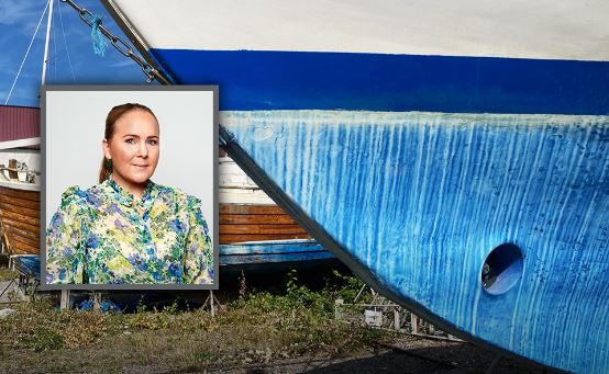 Liten bild på kvinna infälld framför ett båtskrov.