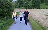 Tre personer går på en gångväg i ett grönområde