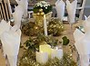 Ett vackert dukat bord med vita servetter i glasen och dekorationer i guldfärg och vita ljus.