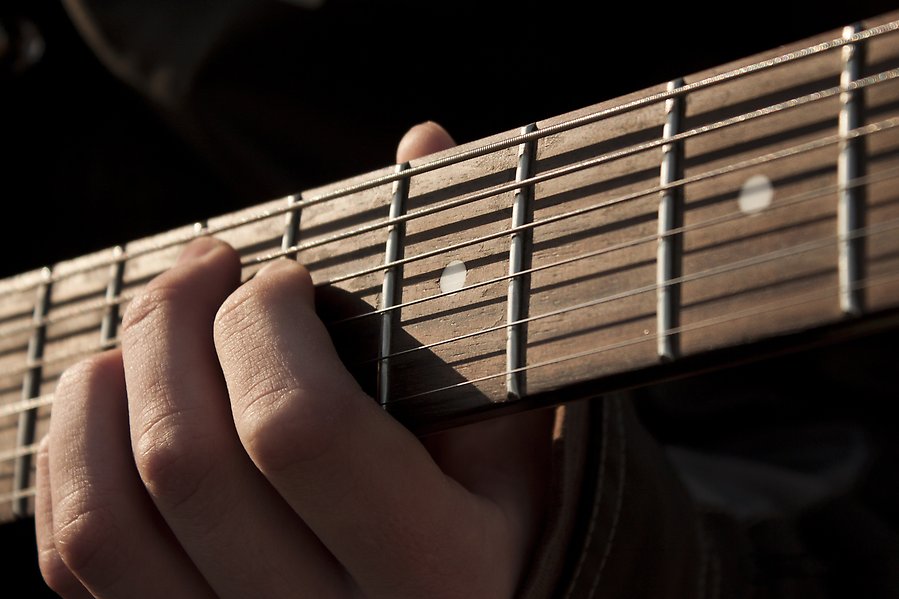 Närbild på en persons händer som spelar gitarr.