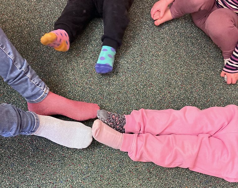Bild på tre barn och en vuxens fötter med olika sockar på sig.