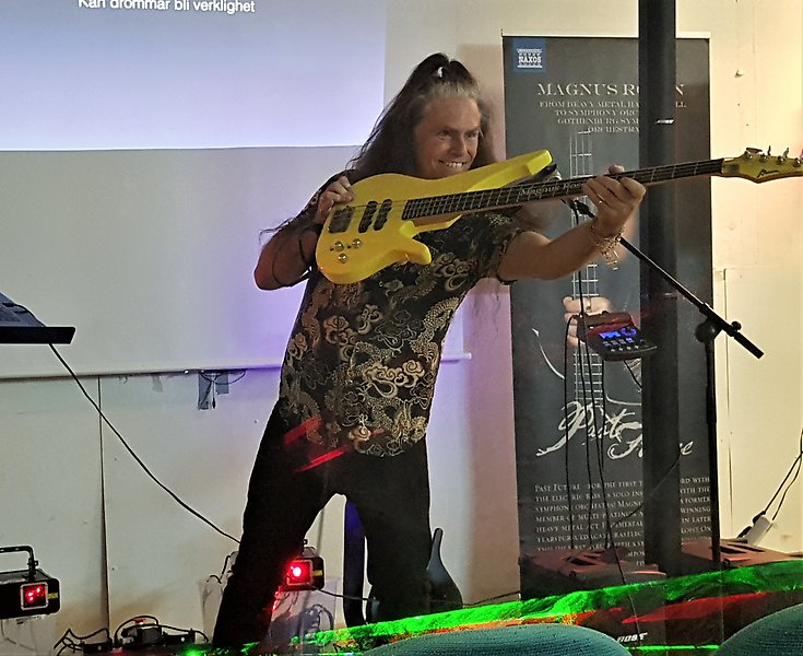 Foto på en man som håller i en gul basgitarr.