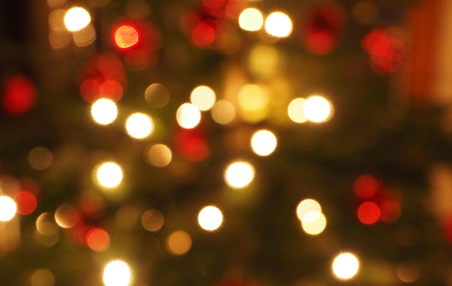 Foto med oskärpa på en julgran med röda kulor och ljus.