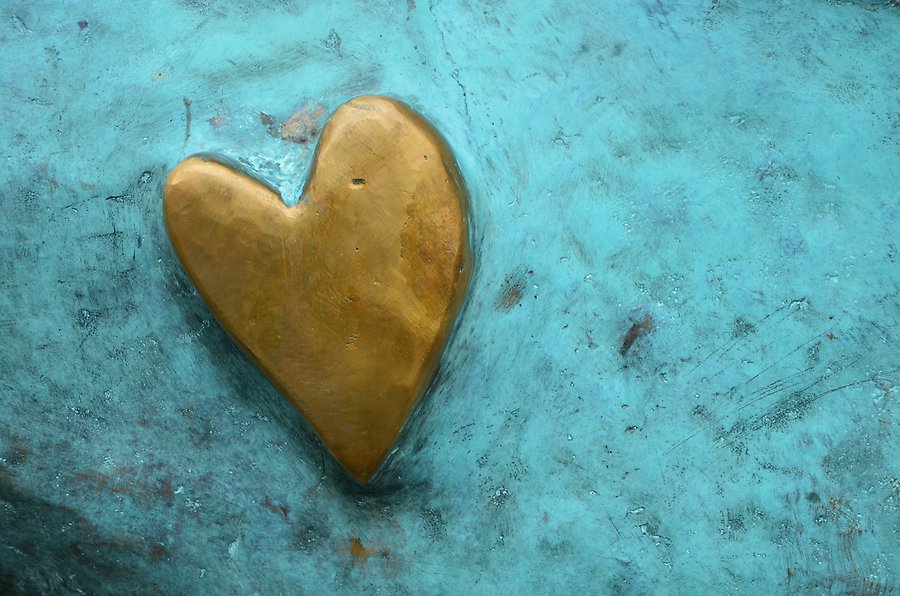 Foto på ett hjärta i guld mot en turkos bakgrund.
