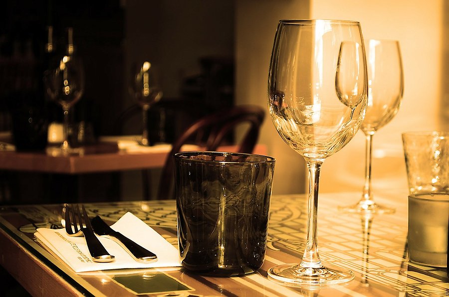Tomma vinglas och bestick på ett bord i en restaurangmiljö.