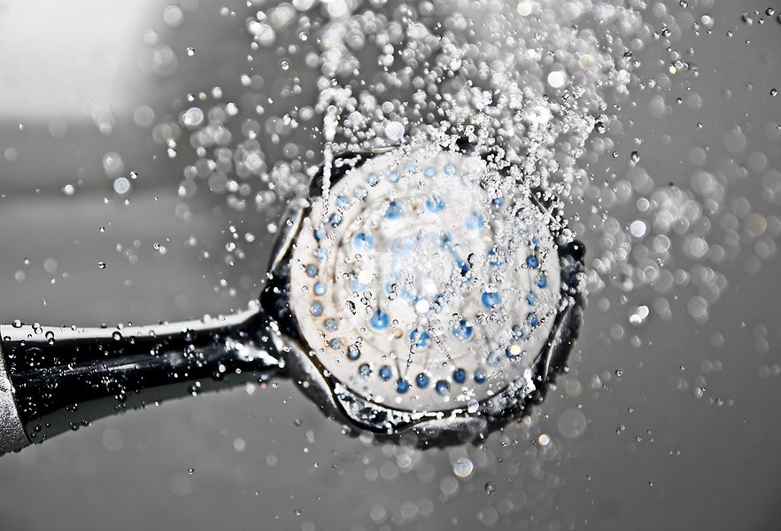 Foto på en ett duschmunstycke som sprutar vatten.