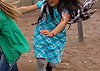 Foto på två flickor som springer på sand på en lekplats. Den ena flickan har mörkblont hår och grön tröja, den andra flickan har mörkbrunt hår och blå klänning.