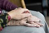 En äldre kvinna som vilar sina händer i knät.