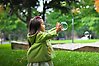 Foto på en flicka som leker med såpbubblor i en park.