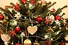 Foto på en julgran med massor av julgransprydnader i form av kulor, hjärtan, stjärnor och girlanger av pärlor.
