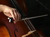Foto på en hand som spelar på en cello, handen håller i en stråke.
