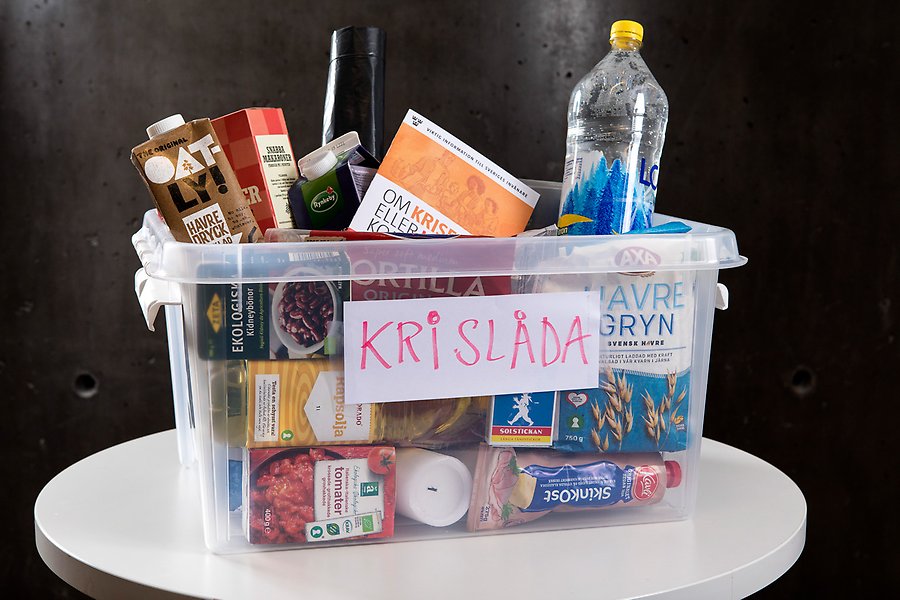Transparent plastlåda med etiketten "krislåda" fylld med matvaror med lång hållbarhet