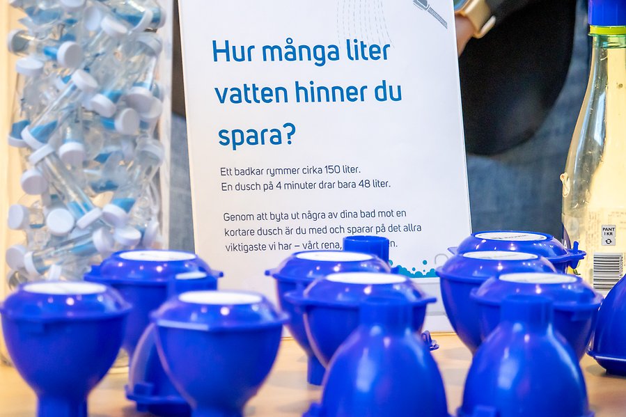 Bild på bord med give-aways och frågan "Hur många liter vatten hinner du spara"