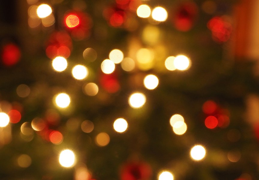 Oskarpt foto på en julgran med julgransljus. Ljusen och julgranskulorna syns som lysande cirklar.