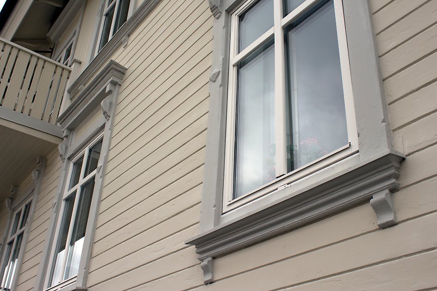 Bild på en husvägg som är lilagrå, med fönster