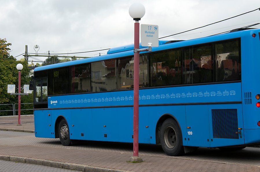 En blå buss står vid en busshållplats.