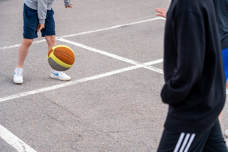 Barn som studsar en boll på en asfaltsplan