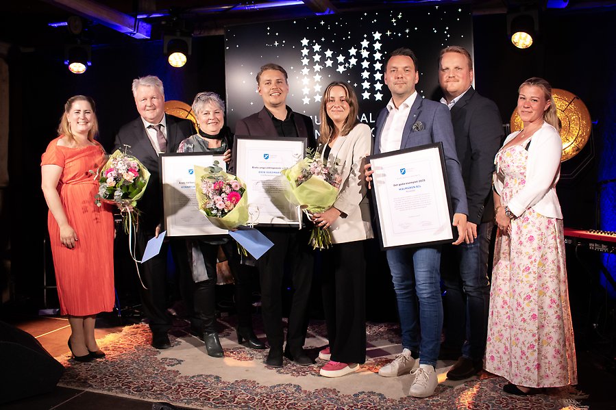Flera personer uppställda för gruppfoto, varav några personer håller upp blommor och prisdiplom.