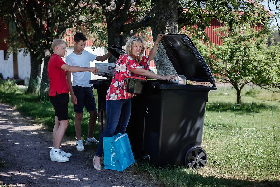 Bild på en liten flicka som källsorterar i hemmet med sina föräldrar.