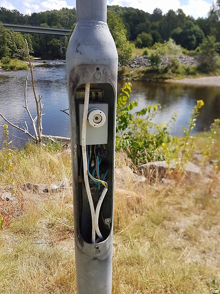 En elstolpe med kablarna exponerade.