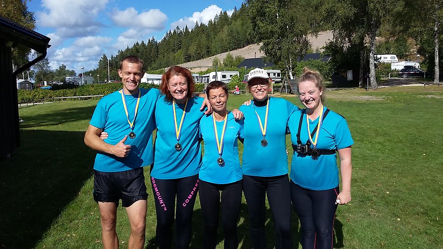 Fem personer i blå tröjor med medaljer kring halsen.